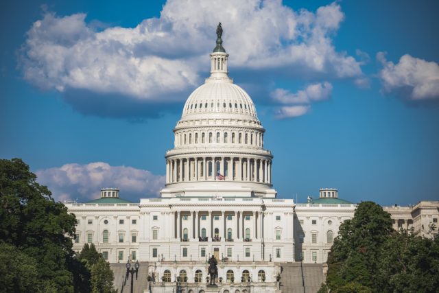 U.S. Capitol Building with white dome and neoclassical architecture against blue sky with clouds